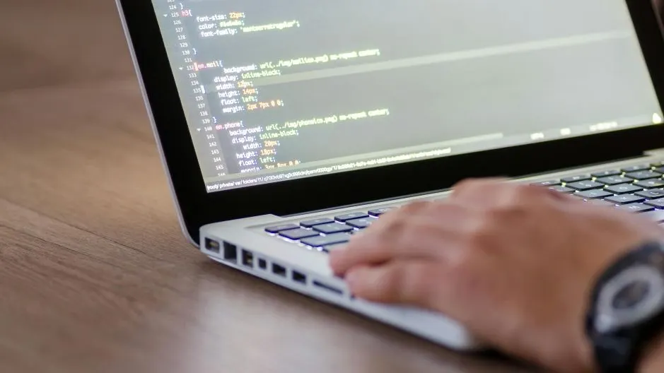 Developer writing live chat scripts on a laptop for customer support.